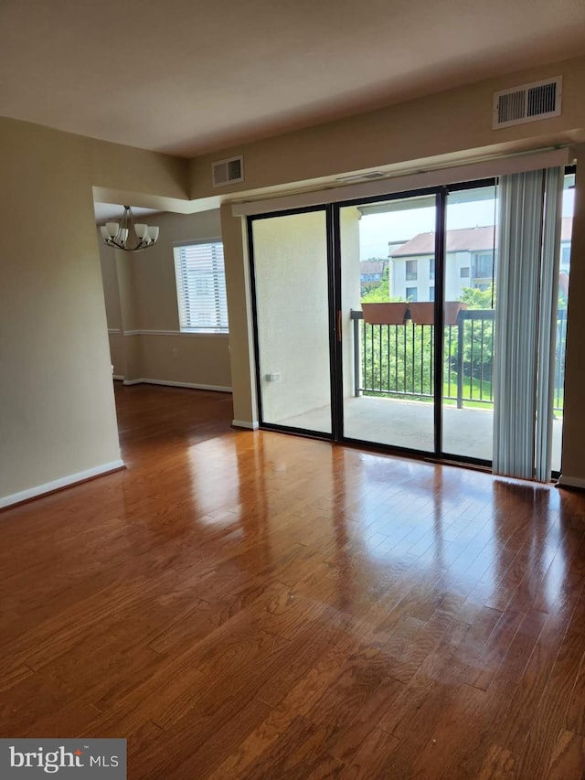 empty room featuring hardwood / wood-style flooring and a notable chandelier