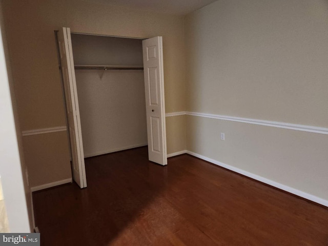 unfurnished bedroom featuring a closet and dark hardwood / wood-style floors