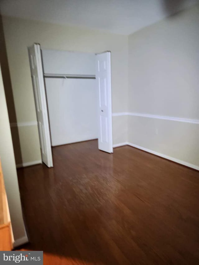 unfurnished bedroom featuring dark wood-type flooring and a closet