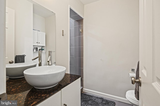 bathroom with vanity, tile patterned flooring, a shower, and toilet