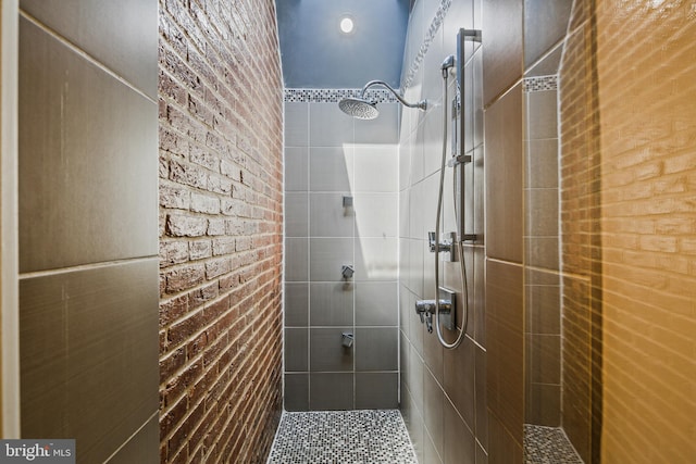 bathroom with tiled shower and brick wall