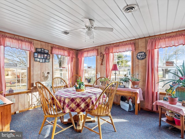 dining space featuring carpet, ceiling fan, wood ceiling, and wood walls