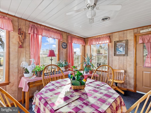 dining area featuring ceiling fan, carpet, and wood walls