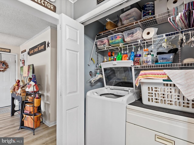 washroom featuring washer and dryer, light hardwood / wood-style floors, and a textured ceiling