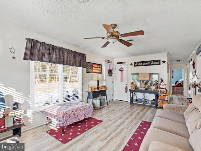 living room featuring light wood-type flooring, ceiling fan, and a textured ceiling