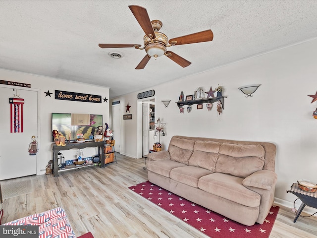 living room with ceiling fan, a textured ceiling, and light hardwood / wood-style flooring