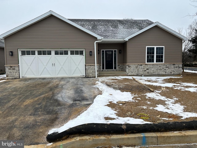 view of front facade with a garage, stone siding, and aphalt driveway