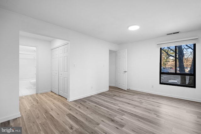 unfurnished bedroom featuring light wood-type flooring and ensuite bathroom