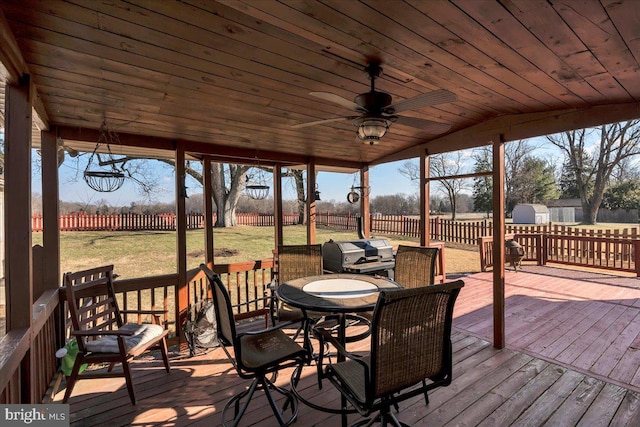 deck with ceiling fan, area for grilling, and a lawn