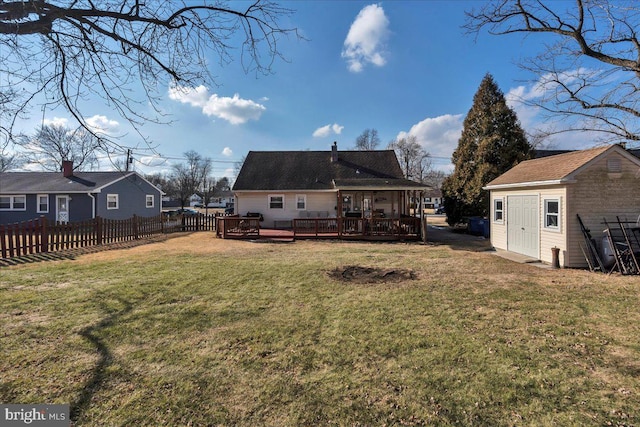 back of house with a wooden deck, a storage shed, and a lawn