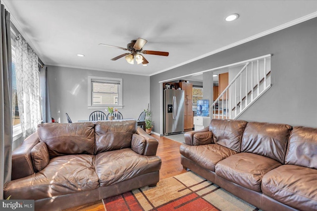 living room with light wood-type flooring, crown molding, and plenty of natural light