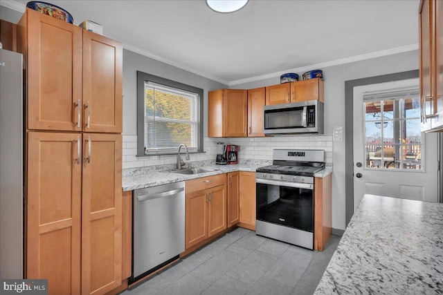 kitchen featuring tasteful backsplash, sink, light stone countertops, appliances with stainless steel finishes, and ornamental molding