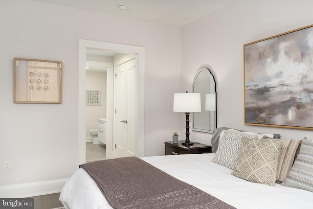 bedroom featuring wood finished floors, baseboards, and ensuite bathroom