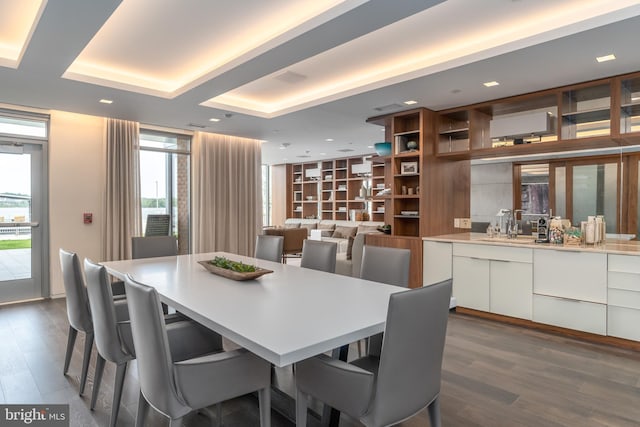 dining area with a tray ceiling, dark wood finished floors, and recessed lighting