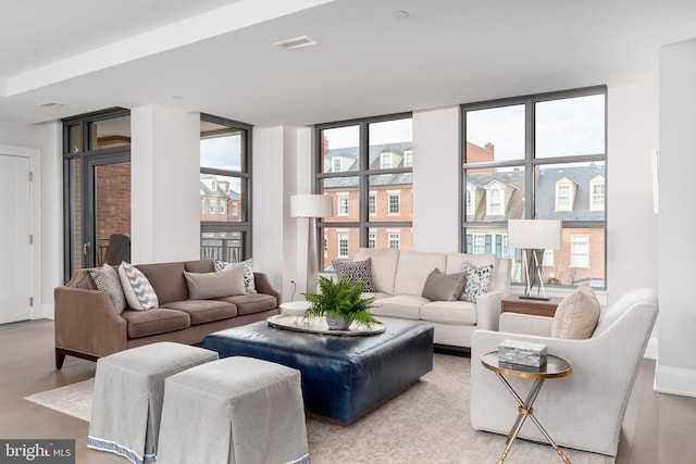 living area with expansive windows, wood finished floors, and visible vents