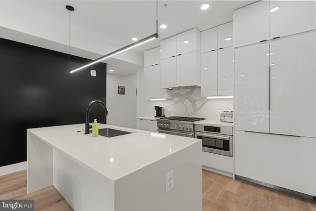 kitchen featuring white cabinetry, a kitchen island with sink, sink, pendant lighting, and stainless steel appliances