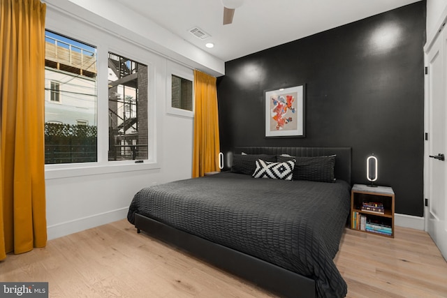 bedroom with ceiling fan, multiple windows, and light wood-type flooring