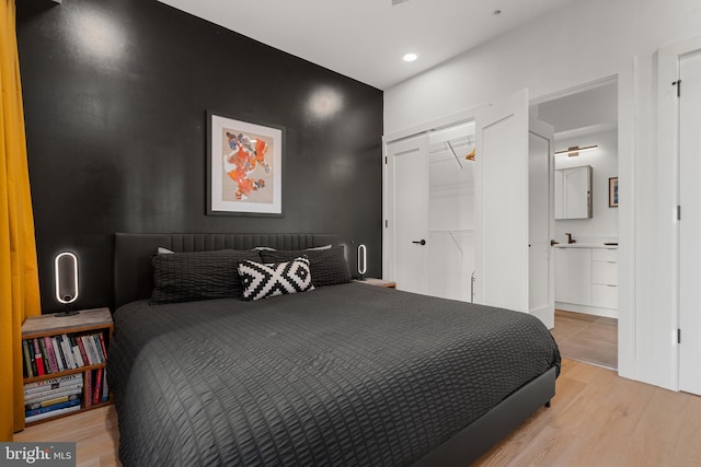 bedroom featuring connected bathroom, a closet, and light hardwood / wood-style flooring