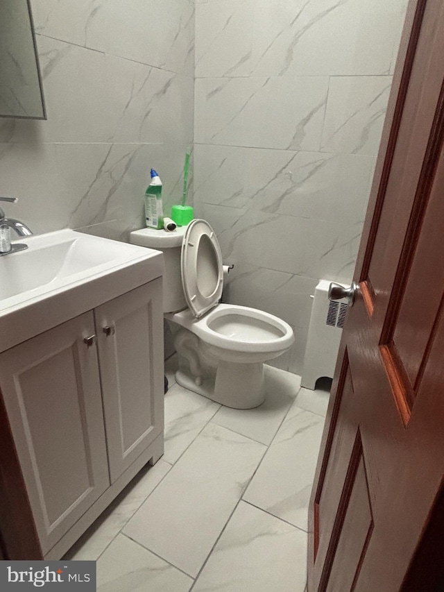 bathroom with vanity, radiator heating unit, tile walls, and toilet