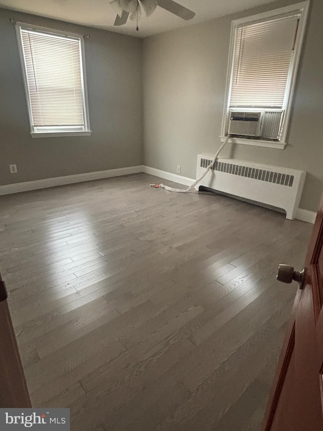 spare room with cooling unit, ceiling fan, wood-type flooring, and radiator