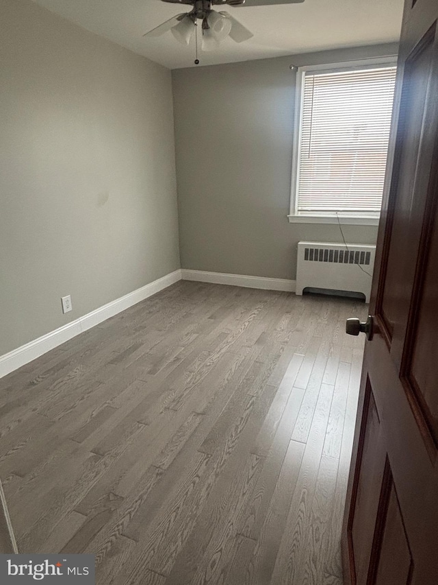 spare room featuring ceiling fan, radiator, and light hardwood / wood-style flooring