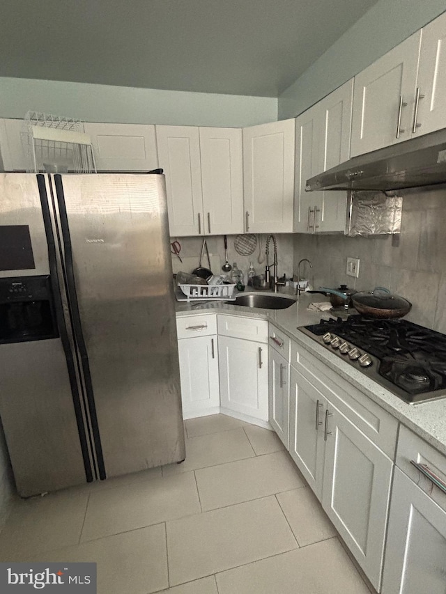 kitchen featuring sink, light tile patterned floors, appliances with stainless steel finishes, white cabinetry, and backsplash