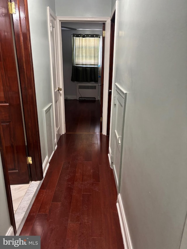 hall with radiator heating unit and dark hardwood / wood-style flooring