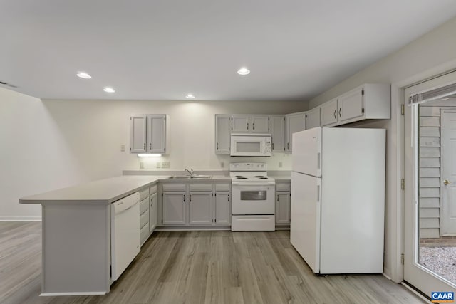 kitchen with white cabinetry, kitchen peninsula, white appliances, light hardwood / wood-style flooring, and sink