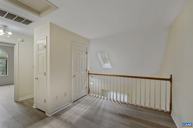 hall with a skylight and light wood-type flooring