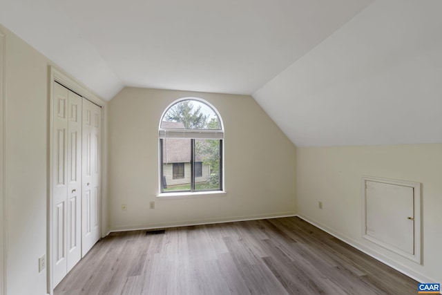 additional living space with lofted ceiling and light hardwood / wood-style flooring