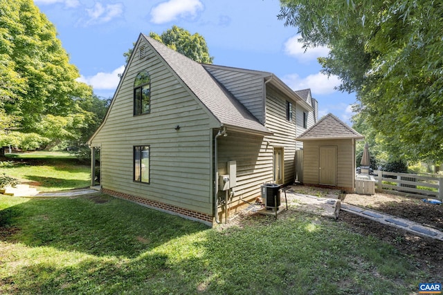 view of home's exterior with central AC unit, a storage shed, and a yard