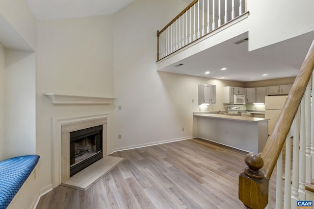 living room with a high ceiling, light hardwood / wood-style flooring, and sink