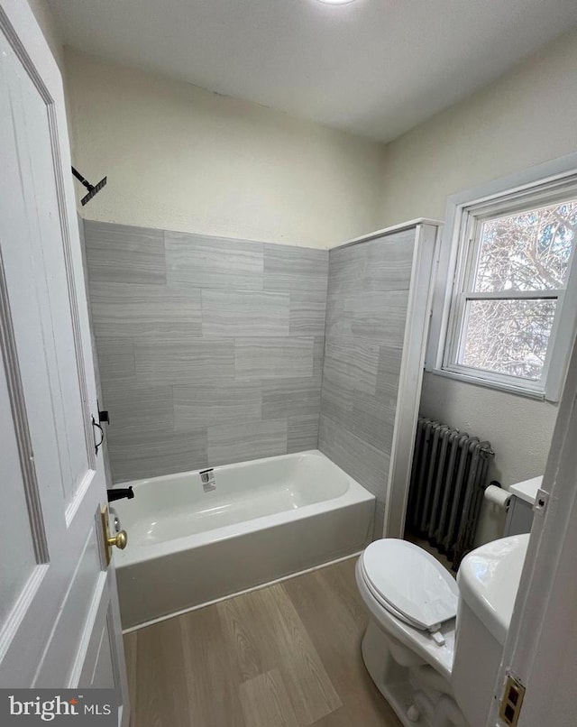 bathroom with  shower combination, toilet, radiator, and hardwood / wood-style floors