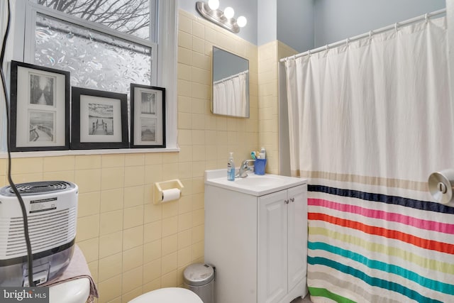 bathroom featuring tile walls, vanity, and toilet