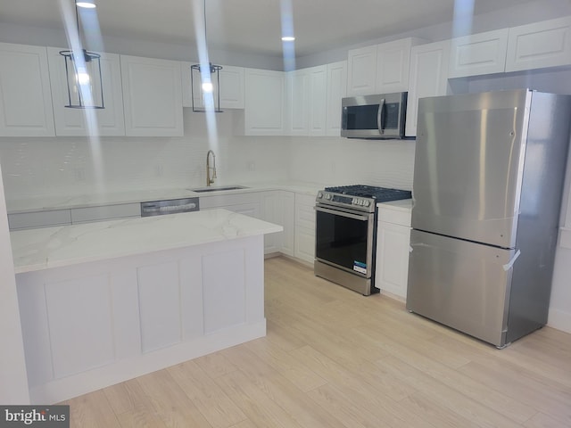 kitchen with stainless steel appliances, white cabinetry, sink, and light stone counters