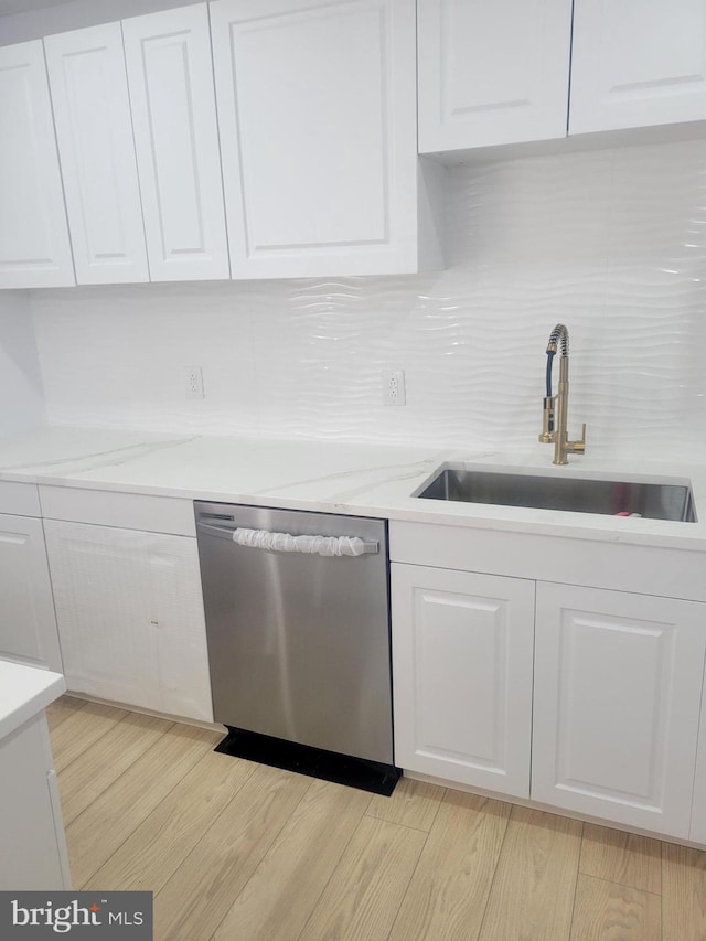 kitchen featuring sink, white cabinetry, light wood-type flooring, stainless steel dishwasher, and decorative backsplash