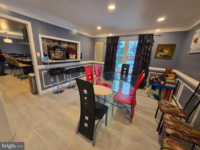 dining room with crown molding and light hardwood / wood-style flooring