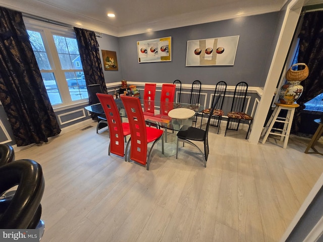 dining room featuring crown molding and light hardwood / wood-style floors