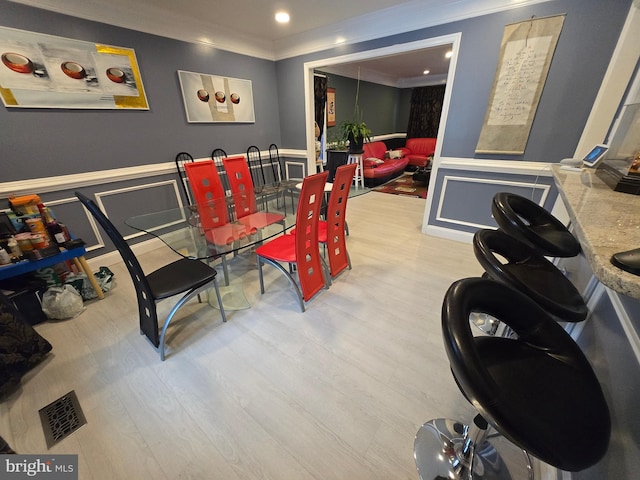 dining space featuring light hardwood / wood-style floors and ornamental molding