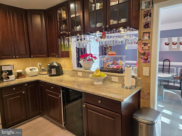 kitchen with decorative backsplash, light stone countertops, beverage cooler, and dark brown cabinets