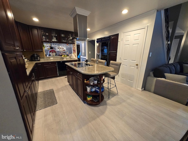 kitchen with a kitchen bar, black electric stovetop, dark brown cabinets, ornamental molding, and an island with sink