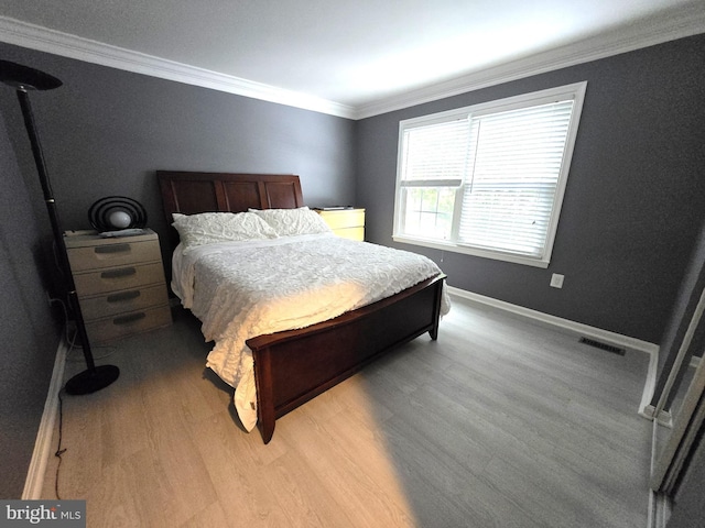 bedroom with ornamental molding and light hardwood / wood-style floors