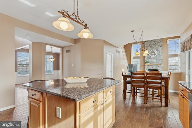 kitchen with dark wood-style floors, hanging light fixtures, a kitchen island, and a wealth of natural light