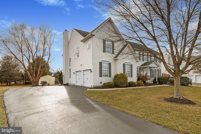 view of front of house featuring a garage, a front yard, driveway, and a chimney