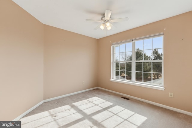 spare room featuring visible vents, baseboards, a ceiling fan, and light colored carpet