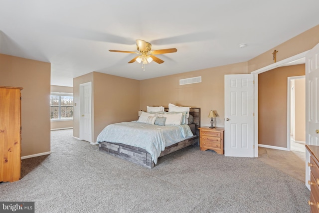 bedroom with light carpet, a ceiling fan, visible vents, and baseboards