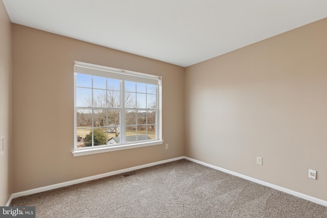 spare room featuring carpet, visible vents, and baseboards