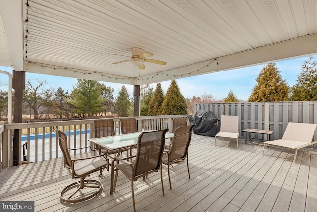 wooden deck with a fenced in pool, a ceiling fan, and outdoor dining space