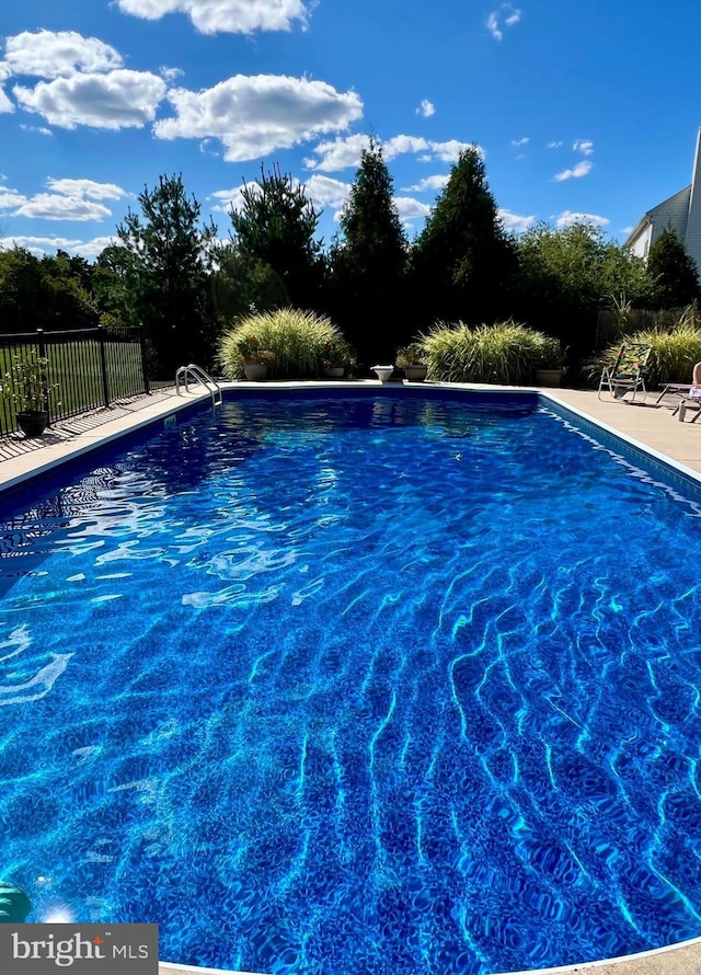 view of swimming pool featuring fence