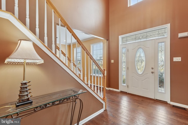 foyer with a high ceiling, dark wood finished floors, visible vents, and baseboards